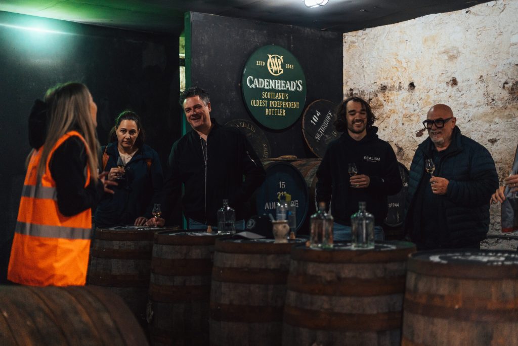 A group tasting whisky among the casks in the warehouse