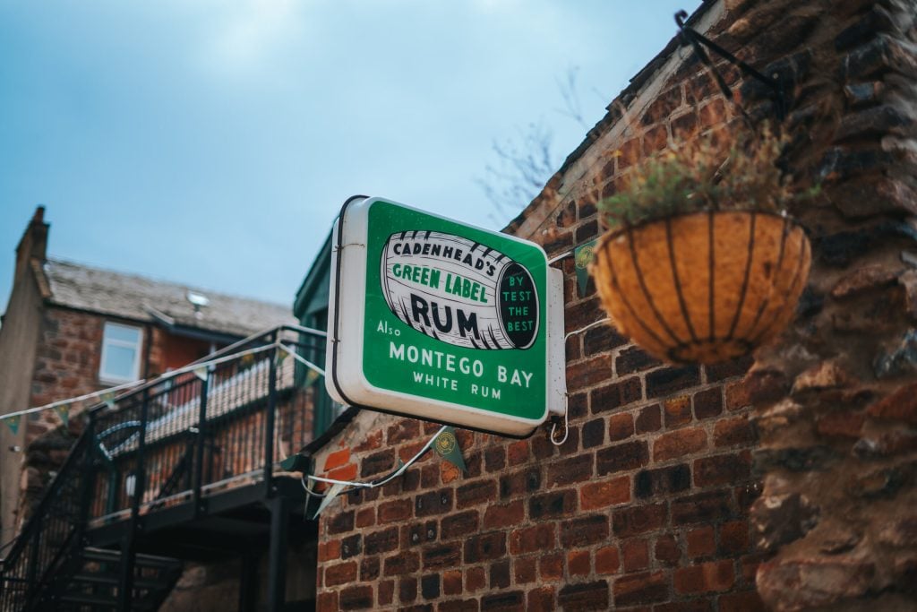 The painted Cadenhead's Green Label Rum sign on a brick wall